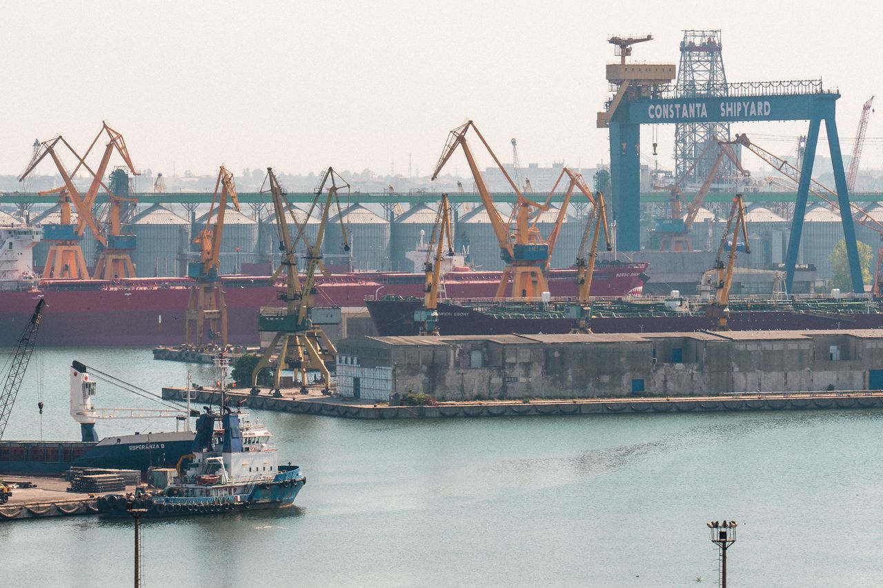 A busy scene at Constanta Shipyard, Romania, featuring cranes and cargo ships in the harbor.