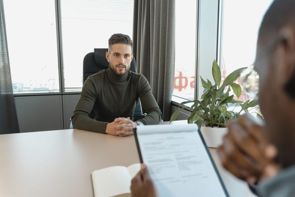 Mastering the First Impression: Your intriguing post title goes here Professional man in turtleneck at office desk during an interview.