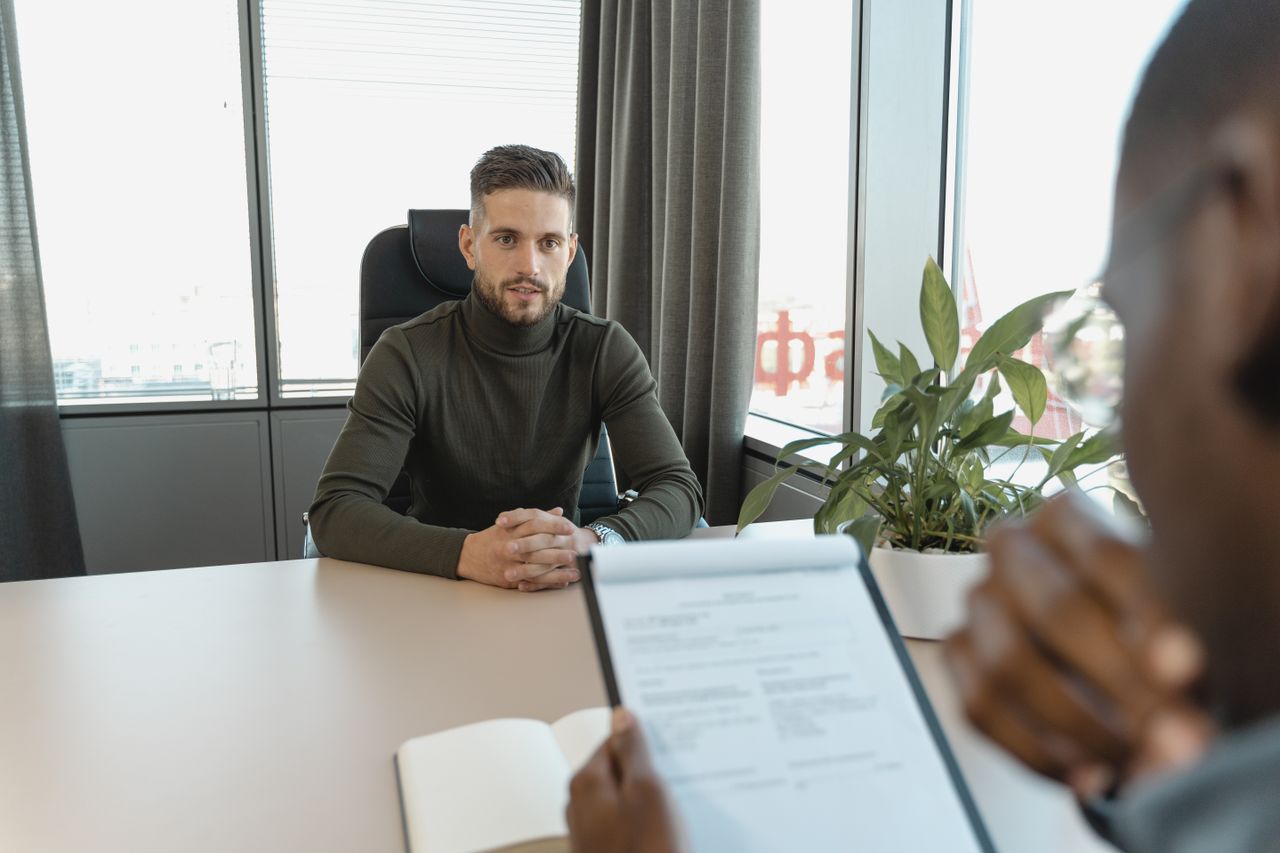Mastering the First Impression: Your intriguing post title goes here Professional man in turtleneck at office desk during an interview.
