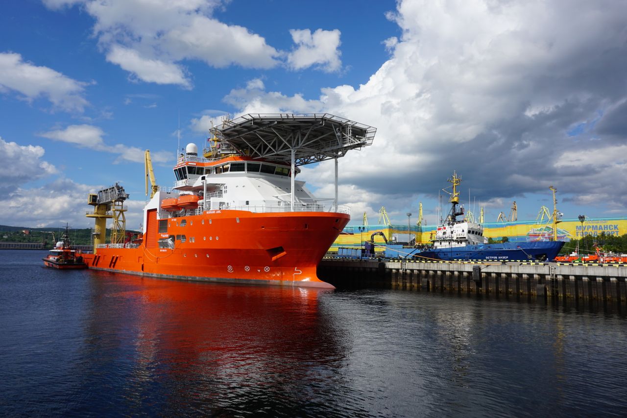 Colorful ships docked at the Murmansk harbor in Russia under a cloudy sky.